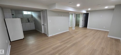 Spacious room with wood-finish flooring, recessed lighting, and a neutral color palette - 13812 63 Street Nw, Edmonton, AB 