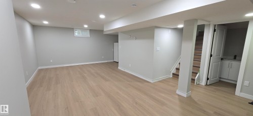 Open-concept finished lower level featuring wood-finish flooring, recessed lighting, a utility sink, and built-in cabinetry - 13812 63 Street Nw, Edmonton, AB 