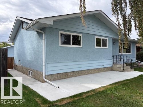 Light blue exterior siding, white window trim, concrete patio, concrete walkway, and black metal handrails - 13812 63 Street Nw, Edmonton, AB 