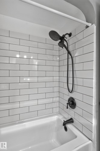 Subway tile shower surround with dark grout, dual-head shower fixture in an oil-rubbed bronze finish, and a white bathtub - 11406 83 Street Nw, Edmonton, AB 