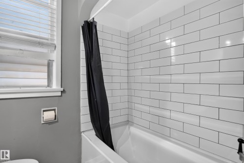 Built-in tub with white subway tile surround and a window with blinds - 11406 83 Street Nw, Edmonton, AB 