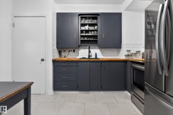 Dark cabinetry with gold-tone hardware, wood-finish countertops, white subway tile backsplash, and stainless steel appliances - 