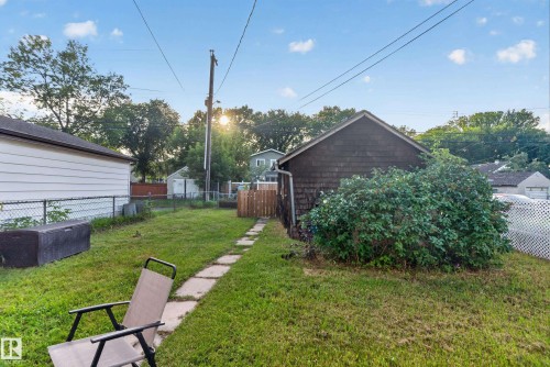 Expansive backyard featuring a stepping stone pathway, mature landscaping, chain link fencing, and a detached structure with shingle siding - 11406 83 Street Nw, Edmonton, AB 