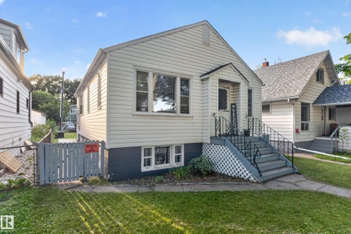 White vinyl siding exterior with a covered entry, concrete steps, and wrought iron railings - 11406 83 Street Nw, Edmonton, AB 