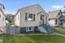 White vinyl siding exterior with a covered entry, concrete steps, and wrought iron railings - 11406 83 Street Nw, Edmonton, AB 