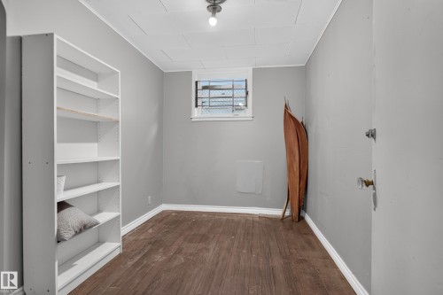 Wood-finish flooring, built-in shelving, window with security bars, and a flush mount ceiling light - 11406 83 Street Nw, Edmonton, AB 