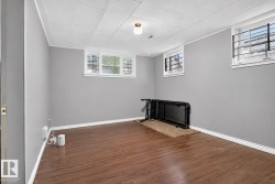Wood-finish flooring, light gray wall paint, and multiple windows with security bars - 