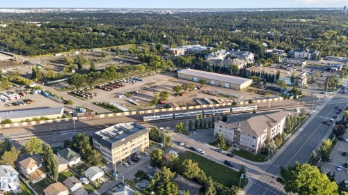Aerial perspective of a mixed-use urban landscape featuring residential buildings, commercial structures, and extensive green spaces - 11406 83 Street Nw, Edmonton, AB 