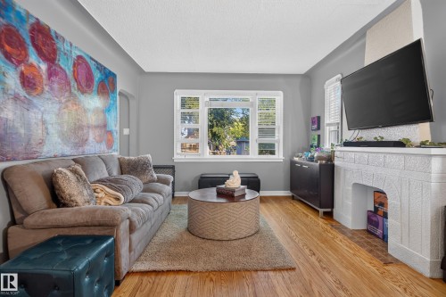 Hardwood flooring, painted walls, window with blinds, built-in fireplace, and overhead lighting - 11406 83 Street Nw, Edmonton, AB 