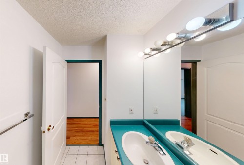 Dual vanity with a turquoise countertop, white undermount sinks, and chrome faucets - 10941 81 Avenue Nw, Edmonton, AB 