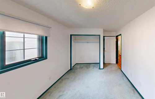 Wall-to-wall carpeting, open closet with hanging rod, window with trim, interior door, and ceiling light fixture - 10941 81 Avenue Nw, Edmonton, AB 