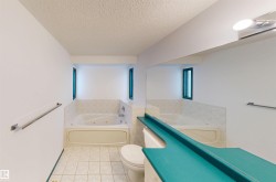 Jetted soaking tub with tiled surround, dual windows, and wall-mounted towel bars - 