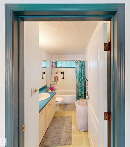 Bathroom featuring a single vanity with a basin sink, built-in cabinetry, a toilet, and a bathtub with a shower - 10941 81 Avenue Nw, Edmonton, AB 