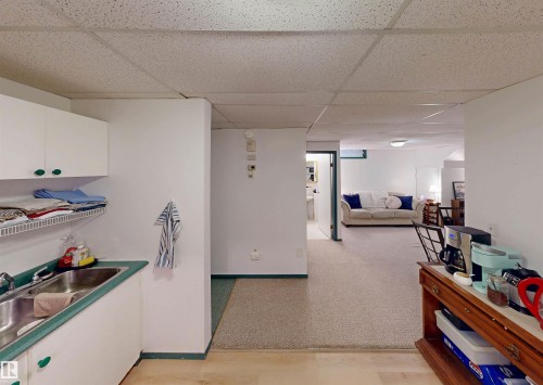Built-in cabinetry with integrated sink, drop ceiling, and mixed flooring surfaces - 10941 81 Avenue Nw, Edmonton, AB 