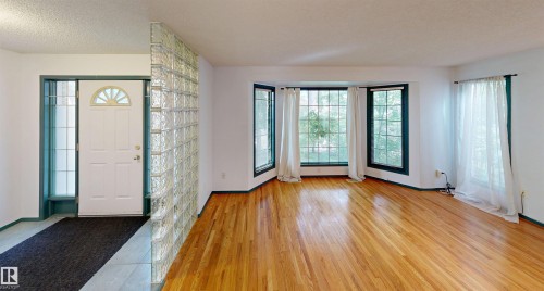 Entryway featuring a glass block partition, wood-finish flooring, and bay windows - 10941 81 Avenue Nw, Edmonton, AB 