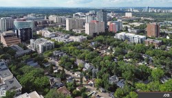 Expansive urban landscape featuring a mix of residential and commercial buildings surrounded by abundant mature trees - 