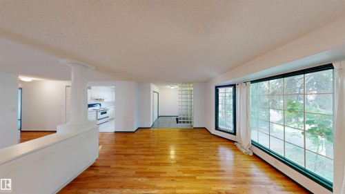 Hardwood flooring, expansive window, architectural column, glass block wall, and white kitchen appliances - 10941 81 Avenue Nw, Edmonton, AB 