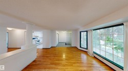Hardwood flooring, expansive window, architectural column, glass block wall, and white kitchen appliances - 
