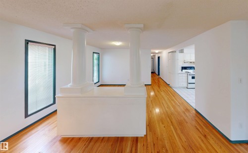 Hardwood-finish flooring, white painted walls, white ceiling, white kitchen cabinetry, and built-in architectural columns - 10941 81 Avenue Nw, Edmonton, AB 