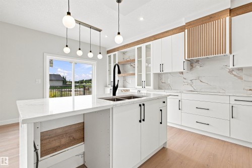 White cabinetry paired with a large center island and a matte black faucet - 10458 104 Street, Morinville, AB 