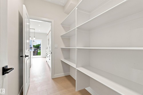 Built-in shelving with crown molding, light wood-finish flooring, and painted interior doors with matte black hardware - 10458 104 Street, Morinville, AB 