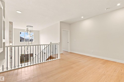 Open concept upper level featuring wood-finish flooring, recessed lighting, and a modern chandelier - 10458 104 Street, Morinville, AB 