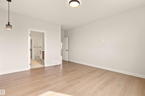 Light wood-finish flooring with white baseboards and light-toned walls - 10458 104 Street, Morinville, AB 
