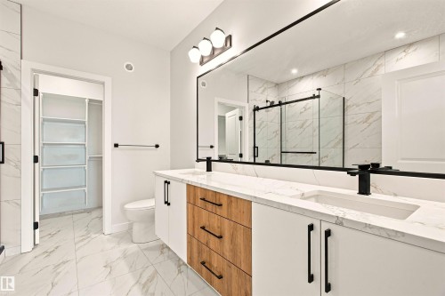 Dual vanity with integrated sinks, wood-finish and white cabinetry, and matte black fixtures - 10458 104 Street, Morinville, AB 
