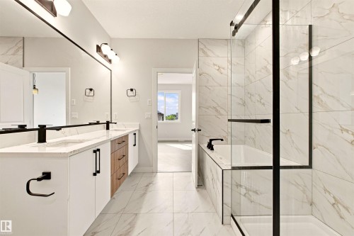 Dual vanity with white cabinetry, wood-finish drawers, and matte black fixtures - 10458 104 Street, Morinville, AB 