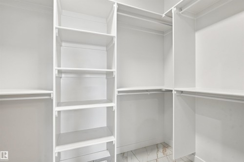 Custom-built closet system featuring multiple shelving units, integrated hanging rods, and tile flooring - 10458 104 Street, Morinville, AB 