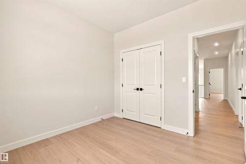 Wood-finish flooring, white walls, and a double-door closet with matte black hardware - 10458 104 Street, Morinville, AB 