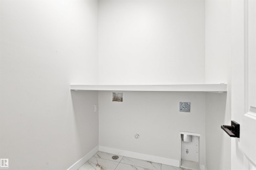Utility area featuring a built-in shelf, white walls, and a drain - 10458 104 Street, Morinville, AB 