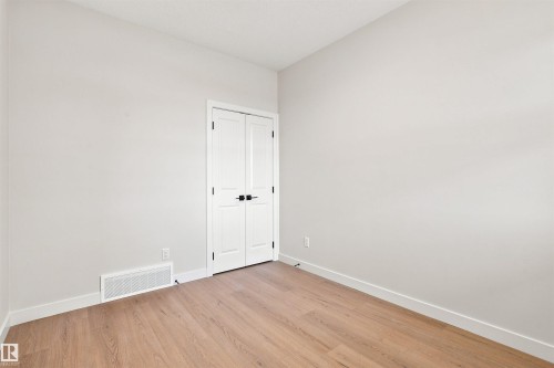 Light wood-finish flooring, white walls, and white trim - 10458 104 Street, Morinville, AB 