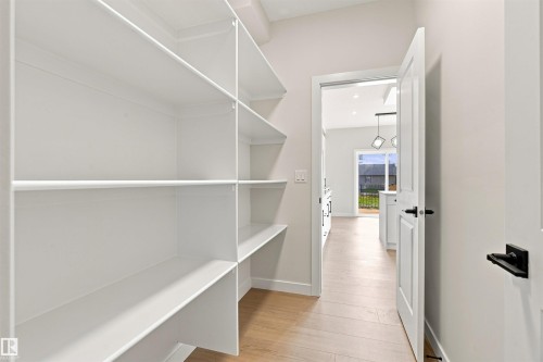 Built-in shelving, white paneled doors, black door hardware, light wood-finish flooring, and recessed lighting - 10462 104 Street, Morinville, AB 