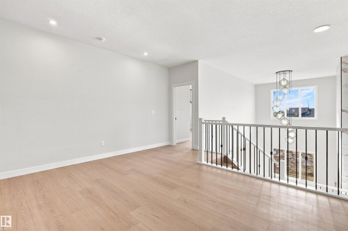 Recessed ceiling lighting, wood-finish flooring, white wall paint, open-concept stairway with black metal balusters, and a contemporary chandelier - 10462 104 Street, Morinville, AB 