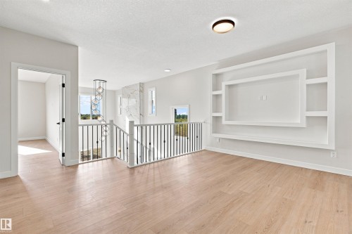 Wood-finish flooring with a custom built-in media center, open railing, and a pendant light fixture - 10462 104 Street, Morinville, AB 
