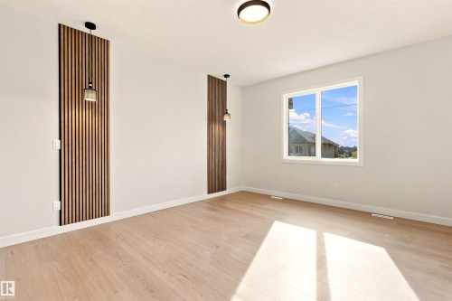 Wood-finish flooring, white walls, two decorative wood slat wall panels, two pendant lights, and a flush-mount ceiling light - 10462 104 Street, Morinville, AB 