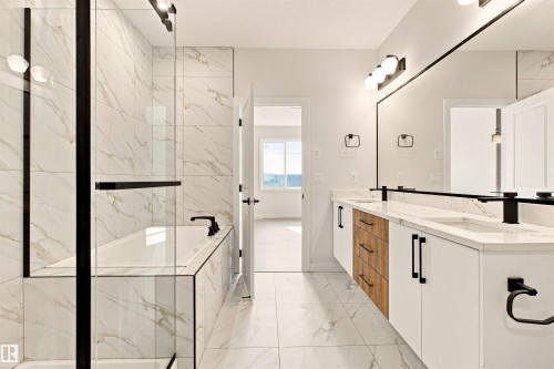 Dual vanity with integrated sinks and white countertops, matte black fixtures, full-width mirror, and built-in cabinetry featuring white and wood-finish doors and drawers - 10462 104 Street, Morinville, AB 