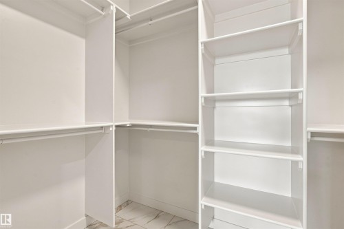 Built-in white shelving, multiple hanging rods, and light-toned tile flooring - 10462 104 Street, Morinville, AB 