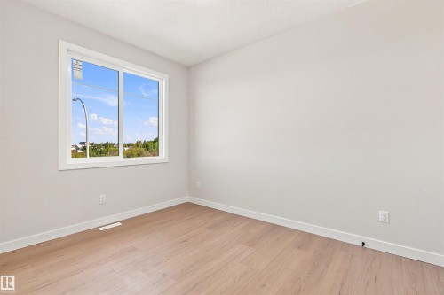 Bright interior with light wood-finish flooring and a white trim window - 10462 104 Street, Morinville, AB 
