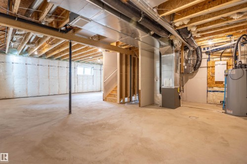 Unfinished lower level with concrete flooring, exposed ceiling joists, framed wall sections, and a visible window - 10462 104 Street, Morinville, AB 