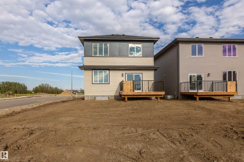 Two-story home with a tan and gray exterior, featuring a private wood deck with black metal railings - 10462 104 Street, Morinville, AB 