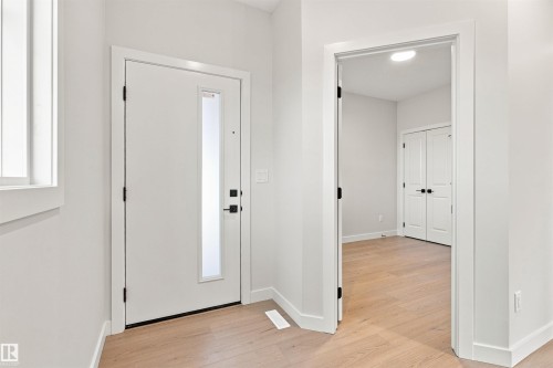 Entryway featuring light wood-finish flooring, a contemporary door with a frosted glass insert, and black hardware - 10462 104 Street, Morinville, AB 