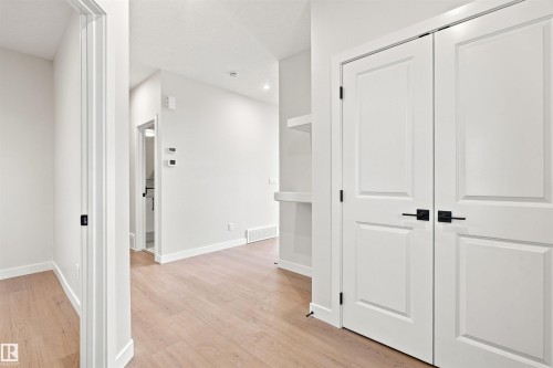 Light wood-finish flooring, white paneled doors with matte black hardware, and recessed lighting - 10462 104 Street, Morinville, AB 