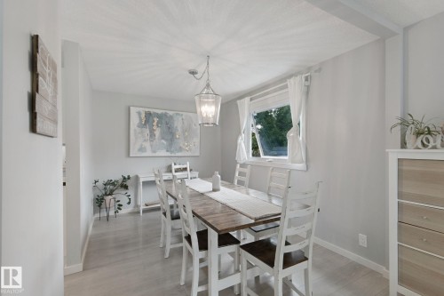 Light-toned wood-finish flooring, a contemporary pendant light fixture, and a window with white trim - 5 Labelle Crescent, St. Albert, AB 