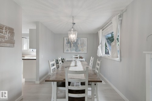 Dining space featuring wood-finish flooring, a contemporary chandelier, and a window with white trim - 5 Labelle Crescent, St. Albert, AB 