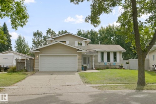 Two-story residence featuring light-colored siding, an integrated garage, a front lawn, and mature trees - 5 Labelle Crescent, St. Albert, AB 