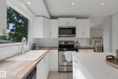 White cabinetry, stainless steel appliances, wood-finish countertops, white subway tile backsplash, and a double basin sink - 5 Labelle Crescent, St. Albert, AB 