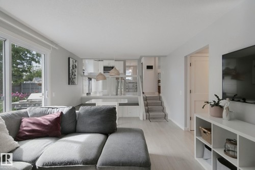 Bright living area featuring light wood-finish flooring and a white built-in media console - 5 Labelle Crescent, St. Albert, AB 