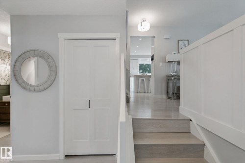 Light wood-finish flooring, white paneled staircase, flush-mount ceiling light fixture, and white bi-fold closet doors - 5 Labelle Crescent, St. Albert, AB 